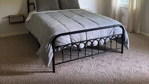 A bedroom with a bed, a ceiling fan, a window with curtains, and a bedside table. - Cozy ranch style home close to Virginia Spearhead and Hatfield McCoy Trailheads  (Pocahontas)