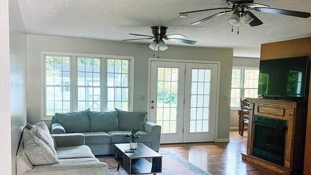 A spacious living room with hardwood flooring, a gray sectional sofa, a coffee table, and a fireplace. - Cozy ranch style home close to Virginia Spearhead and Hatfield McCoy Trailheads  (Pocahontas)