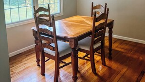A dining area with a wooden table and chairs, a ceiling fan, and a window with a view of greenery. - Cozy ranch style home close to Virginia Spearhead and Hatfield McCoy Trailheads  (Pocahontas)
