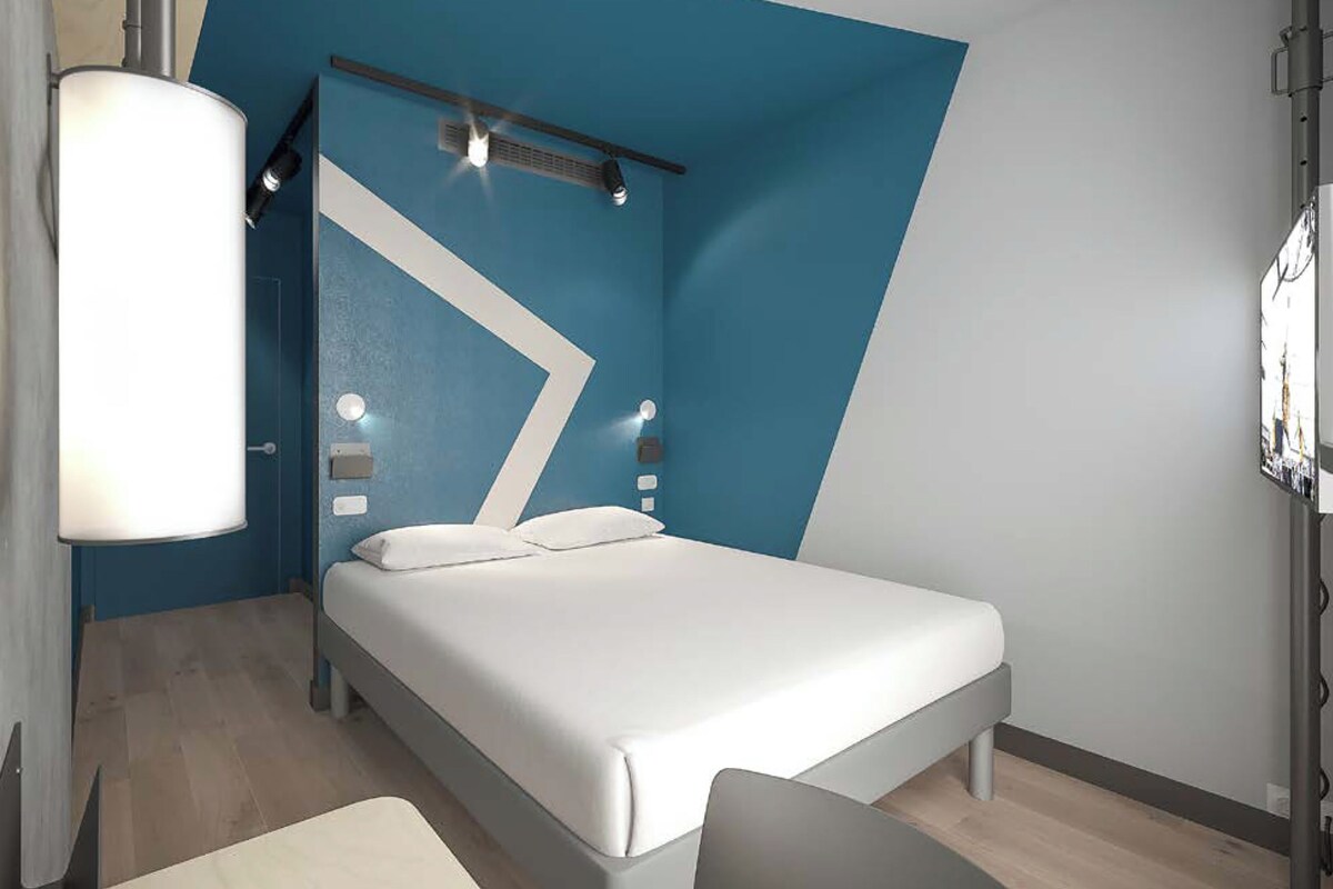Una habitación de hotel moderna con una cama, un escritorio y una silla.