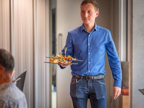 A person in a blue shirt holding a plate with food. - Ibis Budget Nantes Nord Treillières (Treillieres)