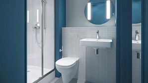A modern bathroom with a glass shower enclosure, a white toilet, and a wall-mounted sink. - Ibis Budget Nantes Nord Treillières (Treillieres)