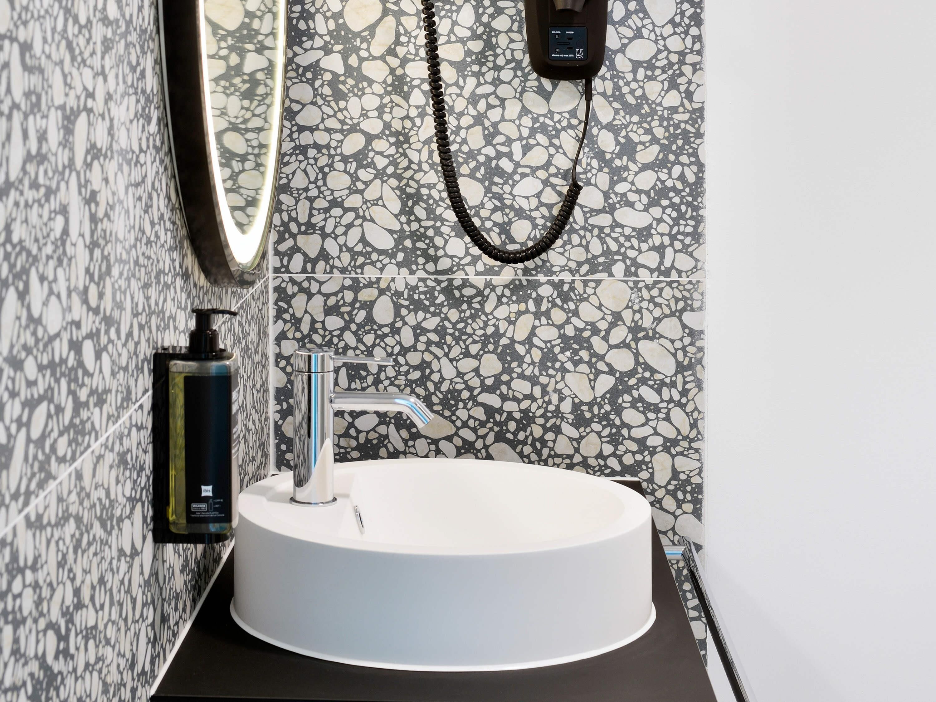 A bathroom with a white sink, chrome faucet, and a mirror.