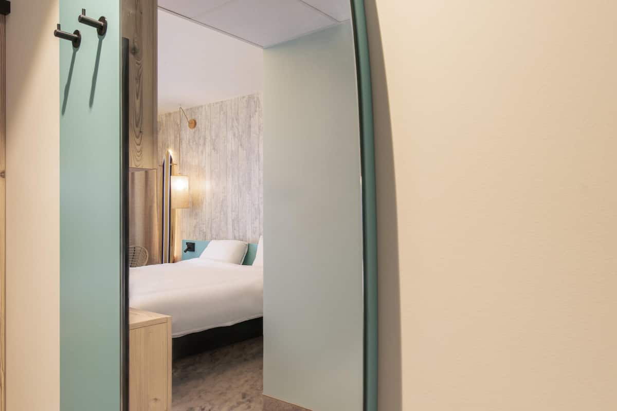 Une chambre à coucher avec un lit, une table de chevet, une lampe et une porte en bois.