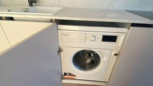 A compact kitchen with a built-in washer and dryer, a sink, and a wooden floor.