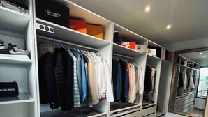 A walk-in closet with multiple shelves and drawers, containing various clothing items and shoes.