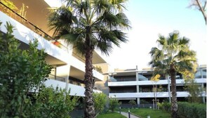 Un bâtiment moderne doté d’une cour intérieure, entourée de palmiers et de verdure.