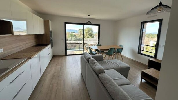 Cozinha moderna com área de refeições, um sofá e vista para o exterior.