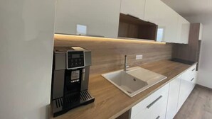 Uma cozinha moderna com máquina de café embutida, pia e armários brancos.