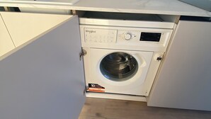 Ein kompakter, moderner Waschraum mit einer Whirlpool Waschmaschine und einem Trockner, einem kleinen Waschbecken und einem Handtuchhalter.
