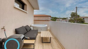 Ein Balkon mit einer Sitzecke, einem Whirlpool und einem Tisch.