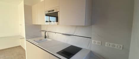 A modern kitchen with white cabinetry, a black countertop, and a built-in oven.