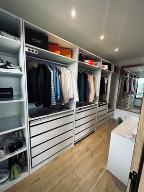 A walk-in closet with multiple shelves, drawers, and hanging space, featuring a variety of clothing and shoes. - Haut de Villa Terrasse Avec Jacuzzi (Fréjus)