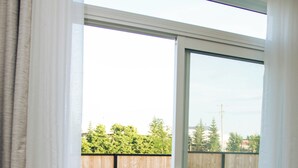 Una habitación con puerta corrediza de vidrio que da a un patio trasero con terraza de madera y zona verde.