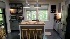 A modern kitchen with a central island, bar stools, and a large window providing natural light. - Trilith Studios Area Lakefront  (Sharpsburg)
