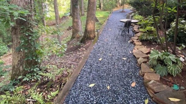 A pathway lined with trees and a small table with chairs, surrounded by greenery. - Trilith Studios Area Lakefront  (Sharpsburg)