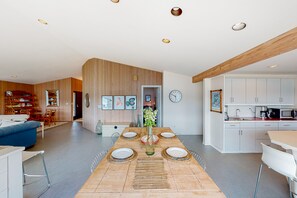 A modern kitchen with white cabinets and a wooden ceiling.