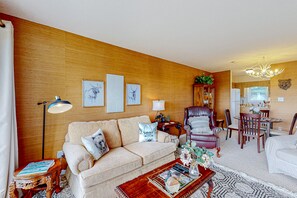 Una sala de estar acogedora con un sofá, sillones, una mesa de centro y un comedor con sillas y una mesa.