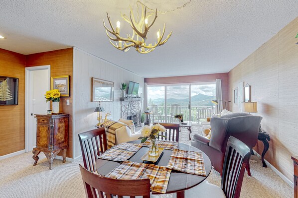 Un comedor con candelabro, mobiliario de madera y vistas al exterior.