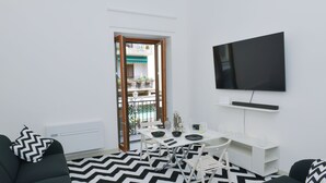 A modern living room with a black and white chevron rug, a black sofa, a white dining table with chairs, and a flat-screen TV mounted on the wall. - Angel's house in Sorrento coast (Meta)