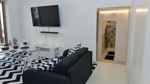 A modern living room with a flat-screen TV, a sofa, a dining table with chairs, and a patterned rug. - Angel's house in Sorrento coast (Meta)