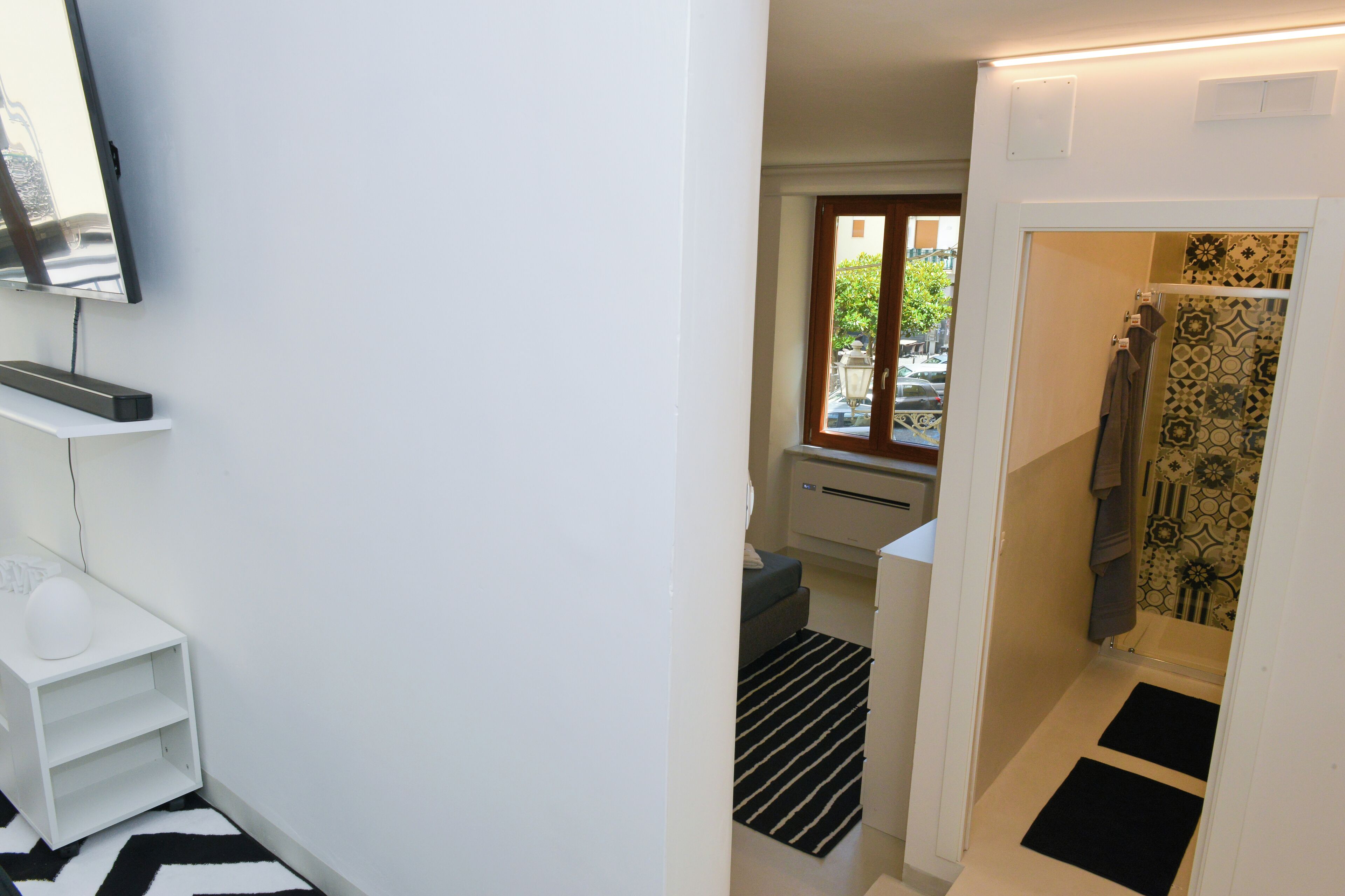 Ein kleines Badezimmer mit Dusche, einem kleinen Fenster und einem weißen Waschbecken.