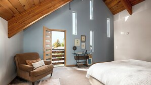 A bedroom with a sloped ceiling, a bed, a chair, a desk, and a door leading to a balcony. - Stunning Repurposed Church, lofted, pet friendly, Free Botanic Garden admit 6 (Denver)