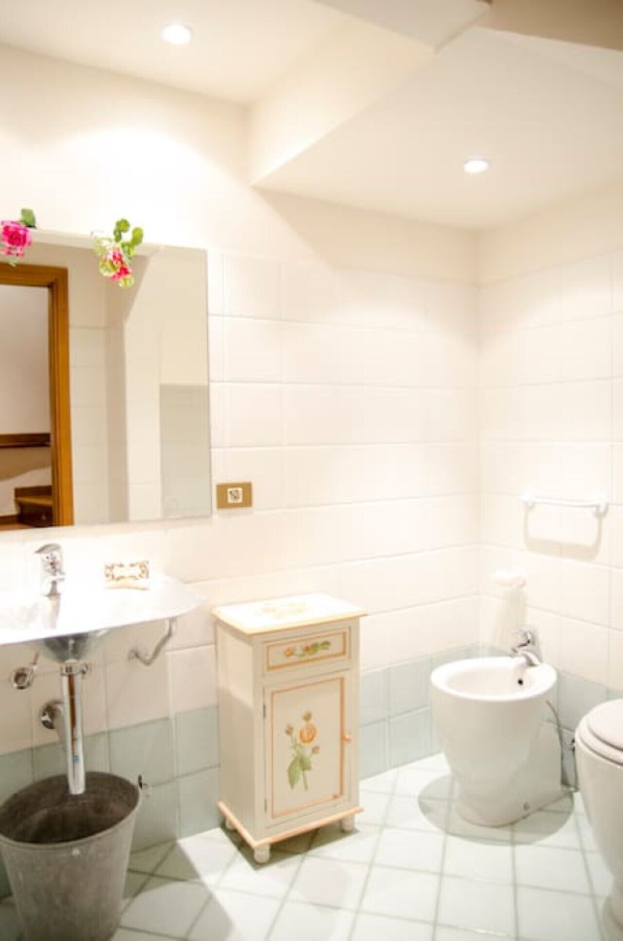 A bathroom with a sink, vanity, bidet, and toilet.