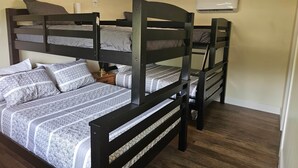 Ein Schlafzimmer mit Etagenbetten, Deckenventilator, Klimaanlage und Holzboden.