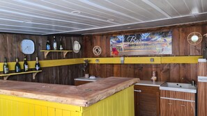 A bar area with wooden walls, a yellow counter, and a clock.