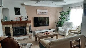Una sala de estar con chimenea, televisor, sofá, sillón y mesa de centro.