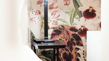 Une lampe de bureau posée sur une table, avec un papier peint à motifs floraux en arrière-plan.