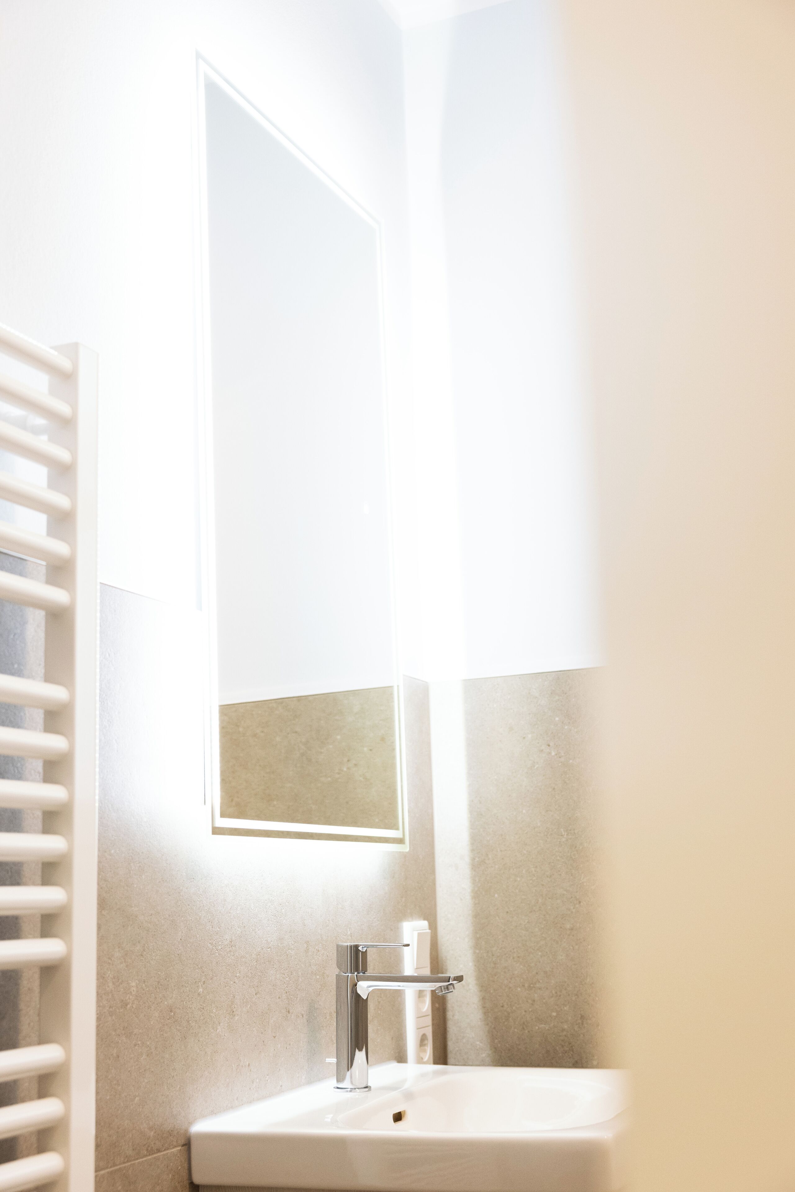 Une salle de bain avec un lavabo blanc, un miroir et un porte-serviettes.