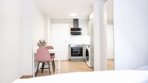 A modern kitchen with a dining area, including a table and chairs, and a washing machine. - House of Blooms (Fulda)