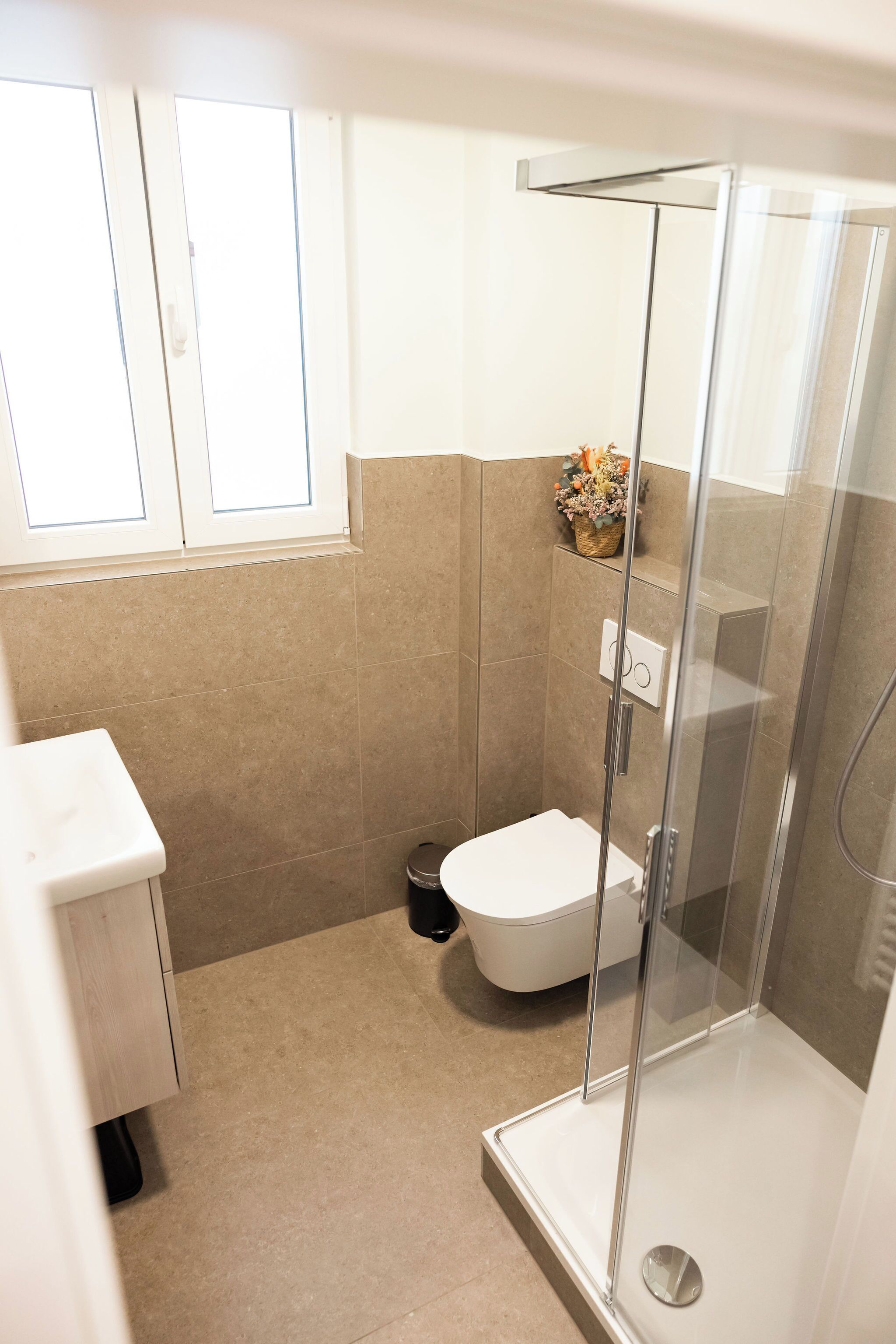 Un baño con ducha de vidrio, inodoro y ventana.