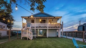 A two-story house with a covered porch and a staircase leading to the upper level. - Casa Rockport - Waterfront + Pet Friendly
 (Rockport)