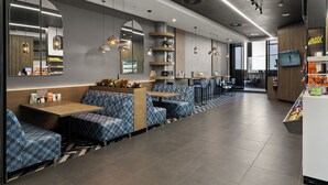 A modern restaurant with blue patterned seating, a counter with a display of snacks, and a TV screen. - Illovo Central 1023 (Sandton)