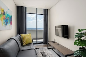Relax in this stylish living room with a sofa, coffee table, and flat-screen TV, offering a view of the outdoors.
