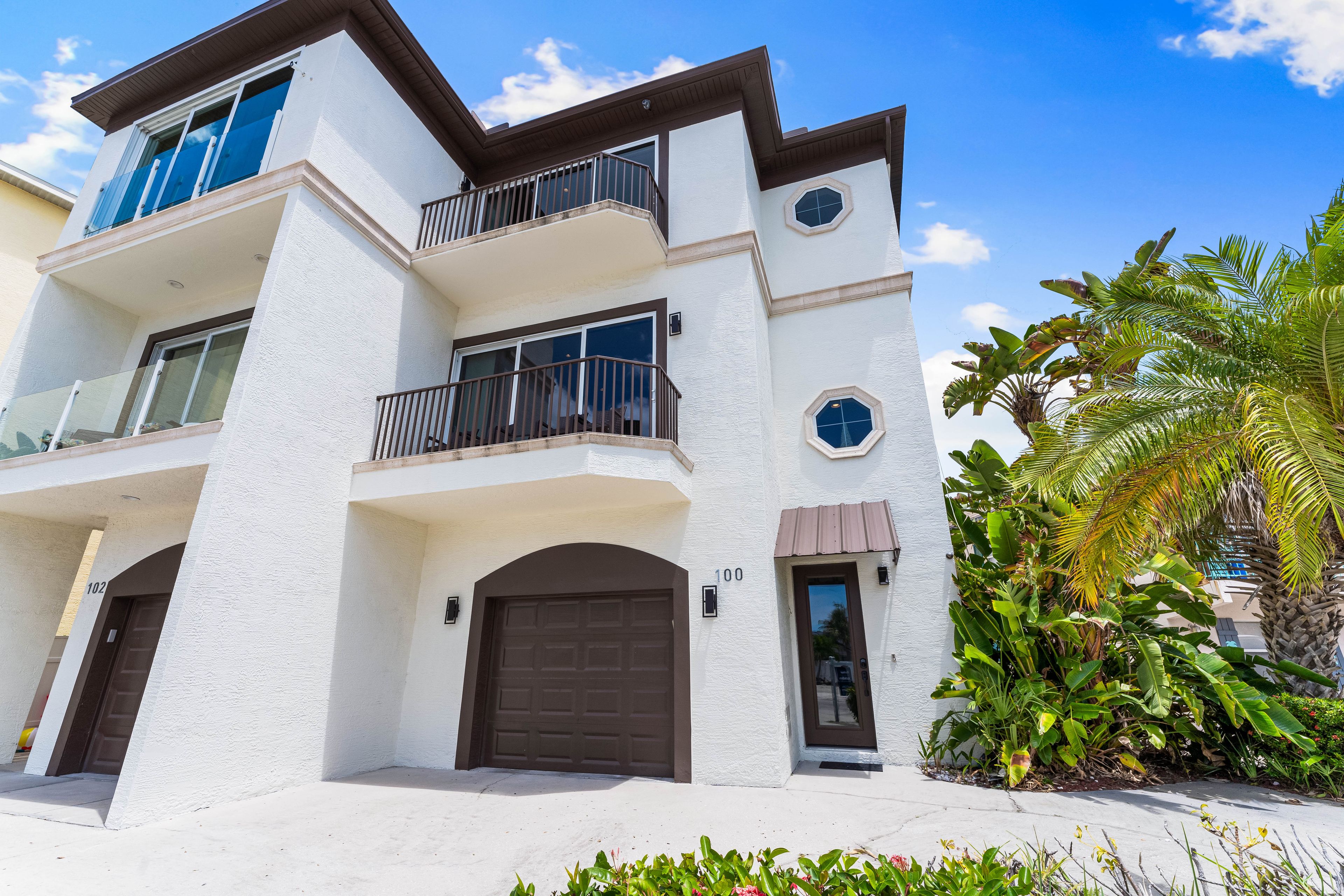 A multi-story residential building with a white exterior, balconies, and a garage door.