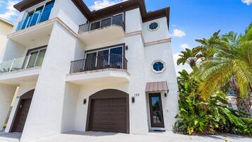 A multi-story residential building with a white exterior, balconies, and a garage door.