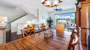 A spacious living room with a wooden floor, a chandelier, a ceiling fan, and a view of the outdoors. - Beachside of the Village by Beachside (Siesta Key)