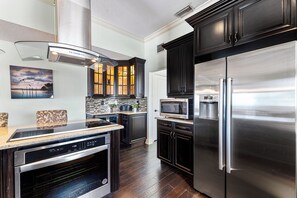 Una cocina moderna con armarios oscuros, electrodomésticos de acero inoxidable y una salpicadera.