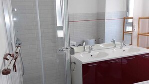 Un bagno moderno con cabina doccia in vetro, due lavabi e un mobile bagno rosso.