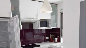 Una cucina moderna con mobili bianchi, un forno a microonde, un forno da incasso e una lampada a sospensione.