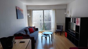 Un soggiorno moderno con un divano, un tavolino, una televisione e un balcone con vista sulla città.