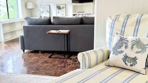 A modern living room with a striped sofa, a coffee table, and a television. - Lookout @ SeaAcres -Beach Access (San Juan County)