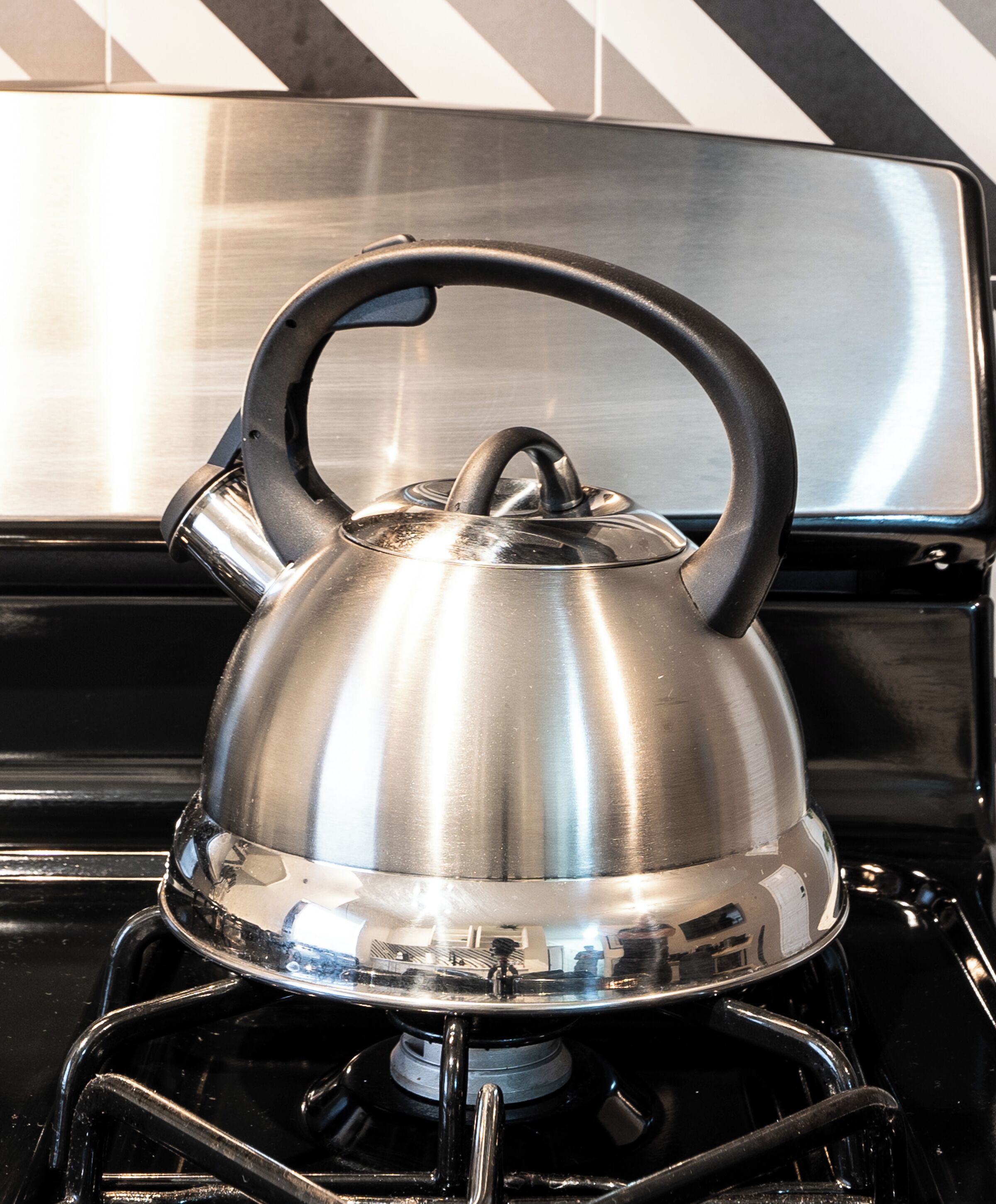 A stainless steel kettle on a gas stove.