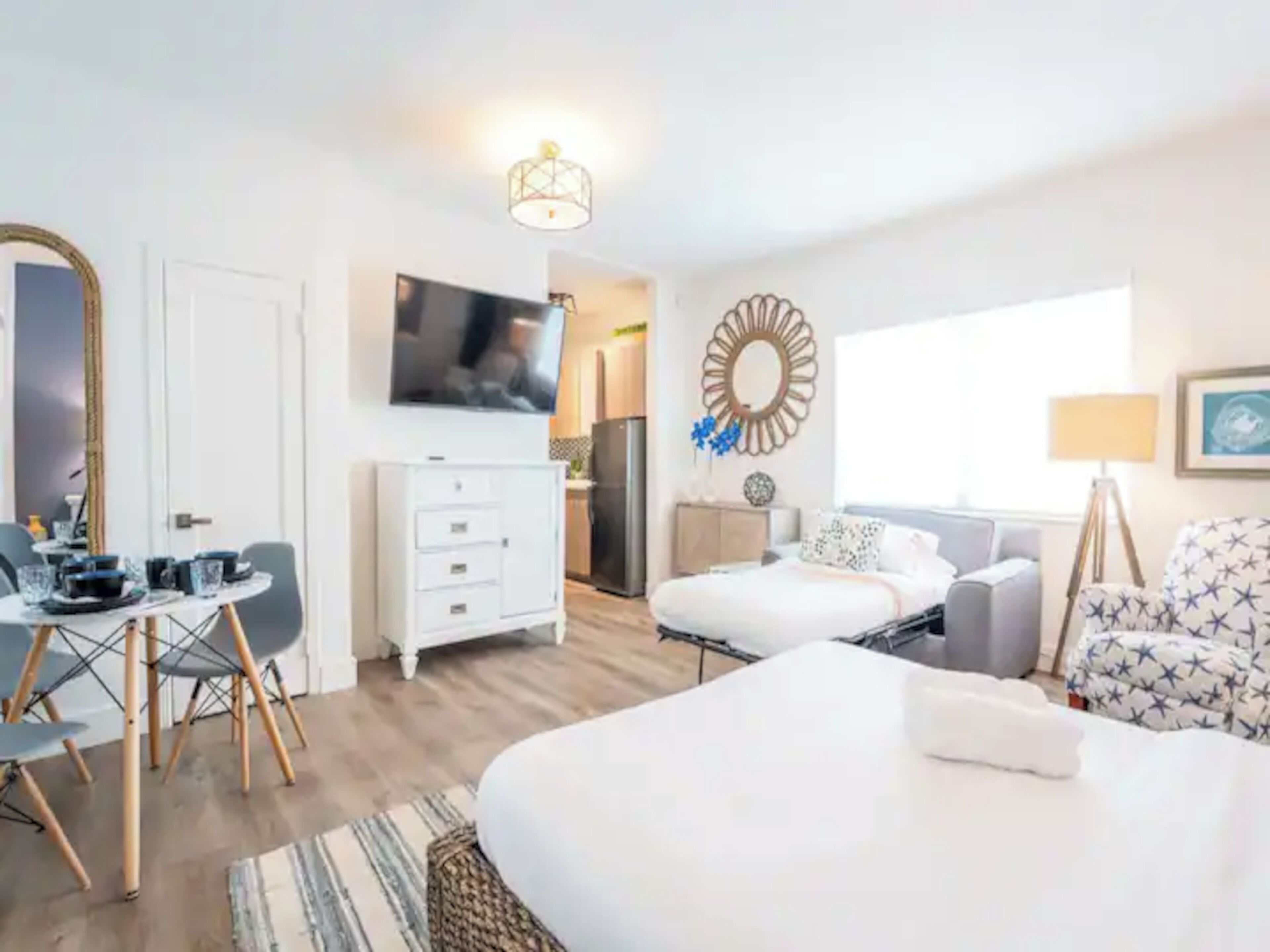 A modern hotel room with a bed, a desk, a chair, a TV, and a window.