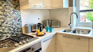 Eine moderne Küche mit Gasherd, Kaffeemaschine, Toaster und einem Fenster mit Blick ins Freie.