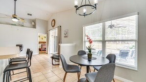 A dining area with a round table, four chairs, a ceiling fan, and a large window with blinds. - 10 Mi to Disney: Home w/ Spa & Heated Pool! (Davenport)